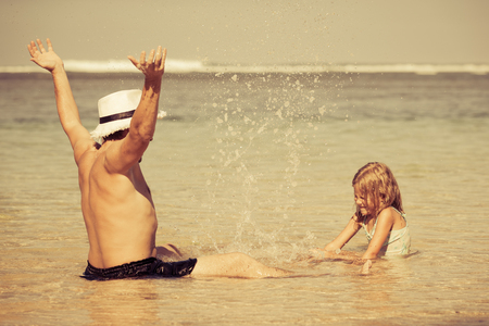 father and daughter playing on the beach at the day timeの写真素材