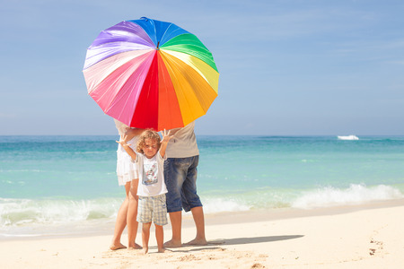 Happy family standing at the beach in the day timeの写真素材