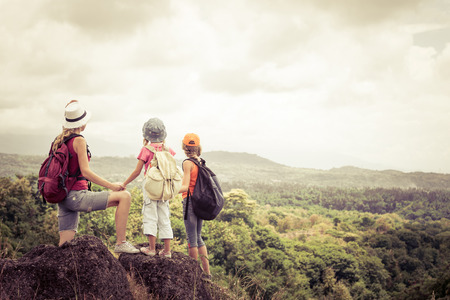 two little kids and mother standing on the mountain at the day timeの写真素材