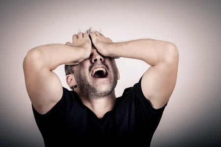 portrait one sad man standing near a wall and covers his face