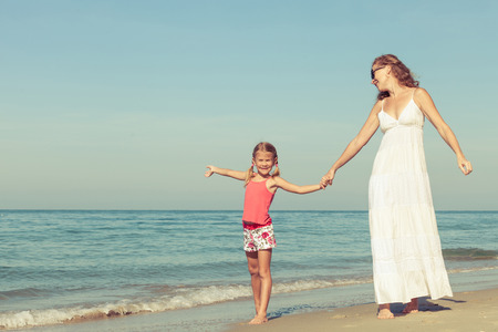 Mother and daughter playing on the beach at the day time. Concept of friendly family.の写真素材