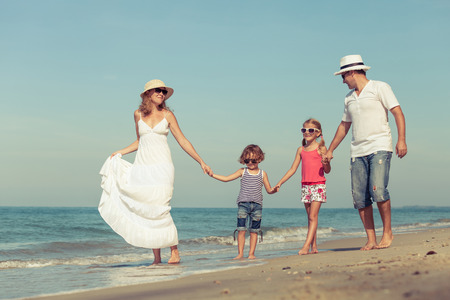 Happy family standing on the beach at the day time. Concept of friendly family.の写真素材
