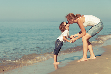 Mother and son playing on the beach at the day time. Concept of friendly family.の写真素材
