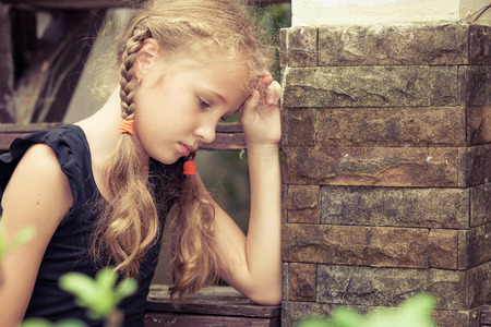 Portrait of sad blond teen girl sitting on the stairs at the day timeの写真素材