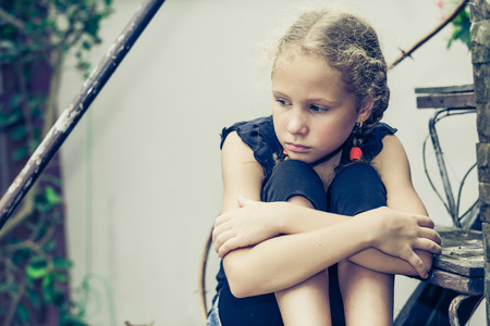 Portrait of sad blond teen girl sitting on the stairs at the day timeの写真素材
