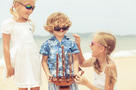 two sisters and brother playing on the beach at the day timeの写真素材