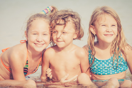 Three happy children  playing on the beach at the day timeの写真素材