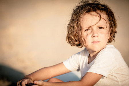 Portrait of little boy sitting on the beach at the day timeの写真素材