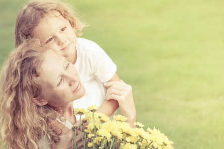 Mother and son playing with flowers on the grass at the day time. Concept of friendly family.の写真素材