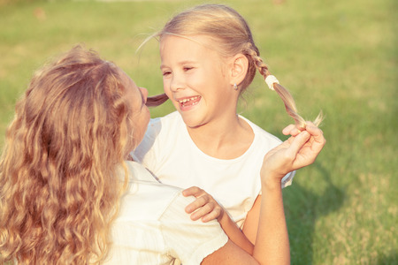 Mother and daughter playing on the grass at the day time. Concept of friendly family.の写真素材