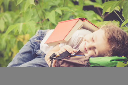 little boy with book lying in the park at the day timeの写真素材