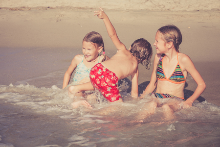 Three happy children  playing on the beach at the day timeの写真素材