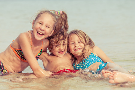 Three happy children  playing on the beach at the day timeの写真素材