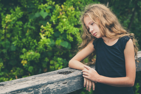 Portrait of sad blond teen girl standing on the bridge at the day timeの写真素材