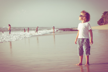 Happy little boy playing on the beach at the day timeの写真素材