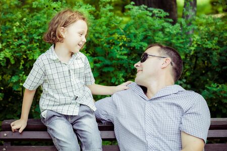 Father and son playing at the park on bench at the day time. Concept of friendly family.