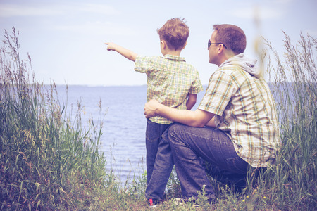 Father and son playing at the park near lake at the day time. Concept of friendly family.の写真素材