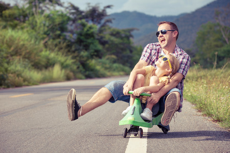 Father and daughter playing on the road at the day time. Concept of friendly family. Father and daughter playing on the road at the day time. Concept of friendly family.