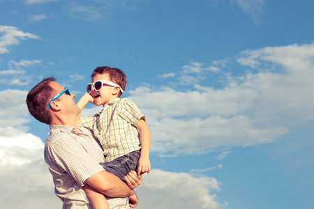 Father and son playing in the park  at the day time. Concept of friendly family. Picture made on the background of blue sky.の写真素材