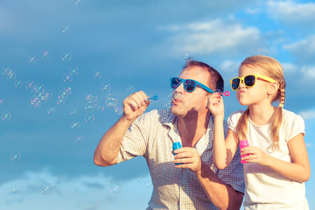 Father and daughter playing in the park  at the day time. Concept of friendly family. Picture made on the background of blue sky.の写真素材
