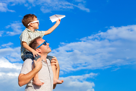 Father and son playing in the park  at the day time. Concept of friendly family. Picture made on the background of blue sky.の写真素材