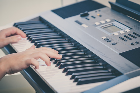Little girl playing synthesizer close up