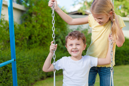 happy brother and sister playing on the playground at the day timeの写真素材