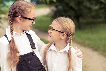 Smiling young school children in a school uniform standing against a tree in the park at the day time. Concept of the girls are ready to go to school.の写真素材