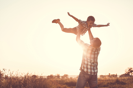 Father and son playing in the park at the sunset time.Family having fun on the field. Concept of friendly family and of summer vacation.の写真素材