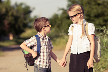 Smiling young school children in a school uniform standing against a tree in the park at the day time. Concept of the children are ready to go to school.の写真素材