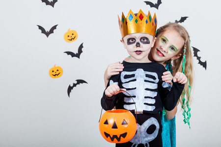 Happy brother and  sister on Halloween party. People having fun indoor. Children wearing costumes  skeletons and witches. Concept of children ready for a party.の写真素材