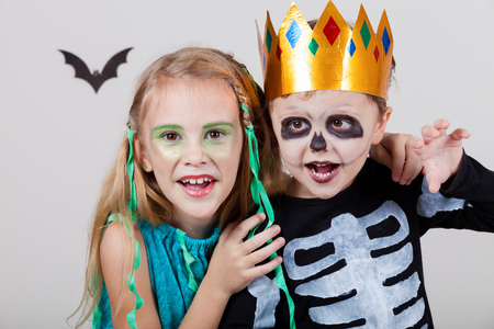 Happy brother and  sister on Halloween party. People having fun indoor. Children wearing costumes  skeletons and witches. Concept of children ready for a party.の写真素材