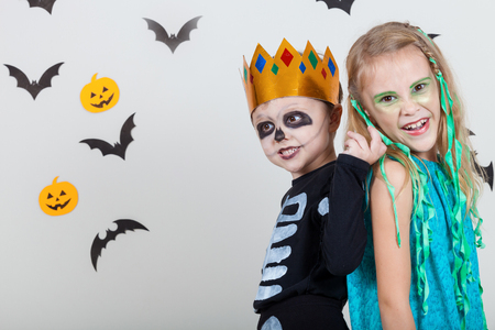 Happy brother and  sister on Halloween party. People having fun indoor. Children wearing costumes  skeletons and witches. Concept of children ready for a party.の写真素材