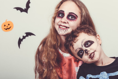 Happy brother and  sister on Halloween party. People having fun indoor. Children wearing costumes  skeletons and zombies. Concept of children ready for a party.の写真素材