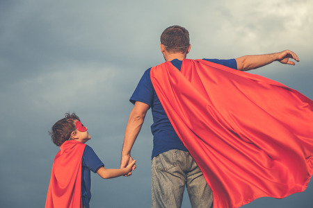 Father and son playing superhero at the day time. People having fun outdoors. Concept of friendly family.