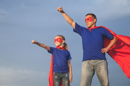 Father and daughter playing superhero at the day time. People having fun outdoors. Concept of friendly family.の写真素材