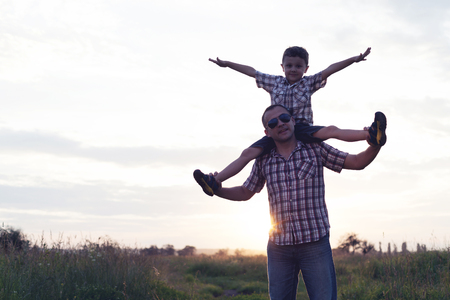 Father and son playing in the park at the sunset time. People having fun on the field. Concept of friendly family and of summer vacation.の写真素材