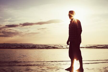 Silhouette of happy man who walking on the beach at the sunset time. People having fun outdoors. Concept of life.の写真素材