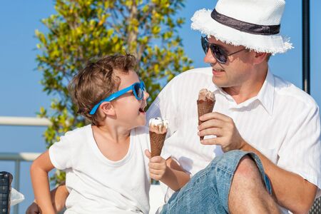 Father and son relaxing near a swimming pool at the day time. People having fun outdoors. Concept of friendly family.の写真素材