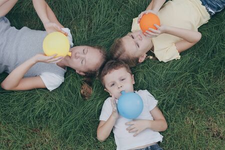 Three happy children playing on the grass at the day time. People having fun outdoors. Concept Brother And Sister Together Foreverの写真素材