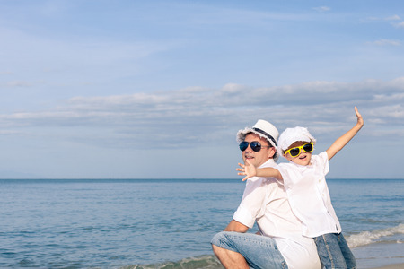 Father and son playing on the beach at the day time. People having fun outdoors. Concept of happy friendly family.の写真素材