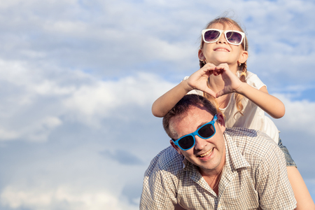 Father and daughter playing in the park  at the day time. Concept of friendly family. Picture made on the background of blue sky.の写真素材