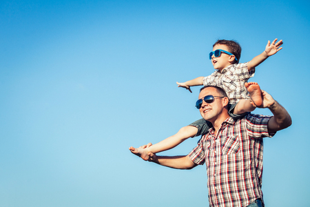 Dad and son in sunglasses playing in the park at the day time. People having fun outdoors.  Concept of friendly family.の写真素材