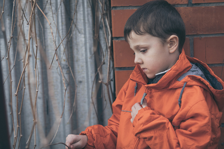 Portrait of sad little boy outdoors at the day time. Concept of dreary spring.の写真素材