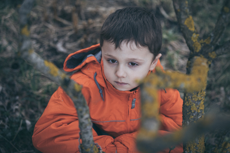 Portrait of sad little boy outdoors at the day time. Concept of dreary spring.の写真素材