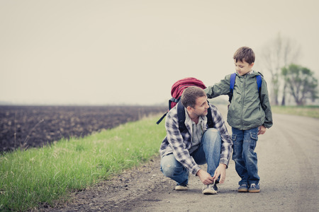 Father and son walking on the road at the day time. People having fun outdoors. Concept of friendly family.の写真素材