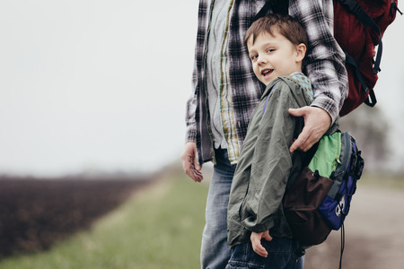 Father and son walking on the road at the day time. People having fun outdoors. Concept of friendly family.の写真素材