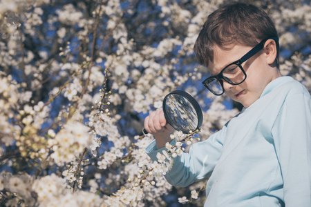 Curious boy studying flowers through a  magnifying glass.の写真素材