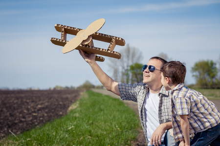 Father and son playing with cardboard toy airplane in the park at the day time. Concept of friendly family.の写真素材