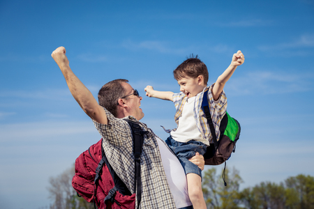 Father and son walking on the road at the day time. People having fun outdoors. Concept of friendly family.の写真素材